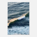 Aerial photo of a golden-lit ocean wave breaking over deep blue-green water, coastal wall art poster