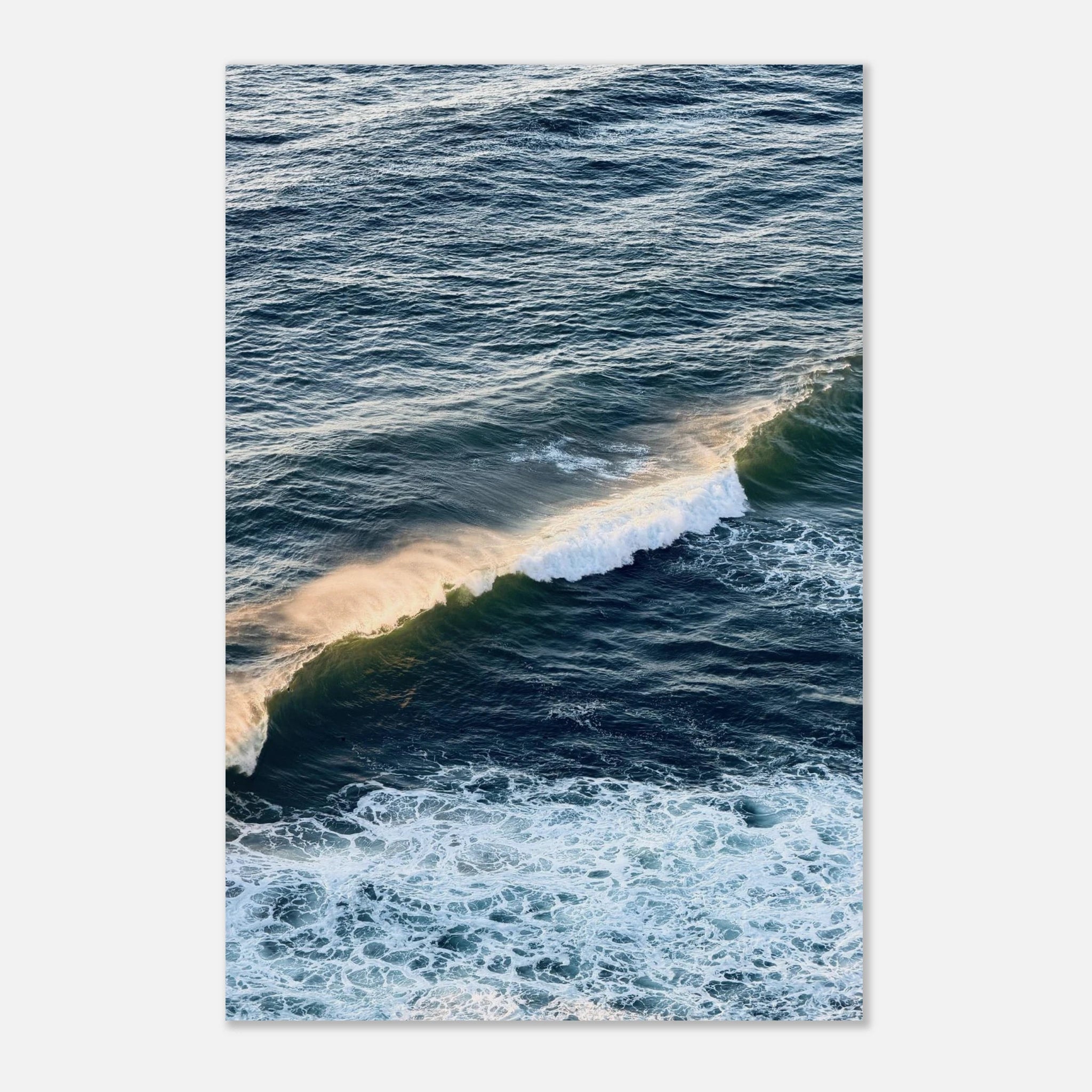 Aerial photo of a golden-lit ocean wave breaking over deep blue-green water, coastal wall art poster