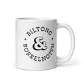 White glossy ceramic mug with black typographic design reading “Biltong & Borrelnoten,” funny South African and Dutch crossover mug.