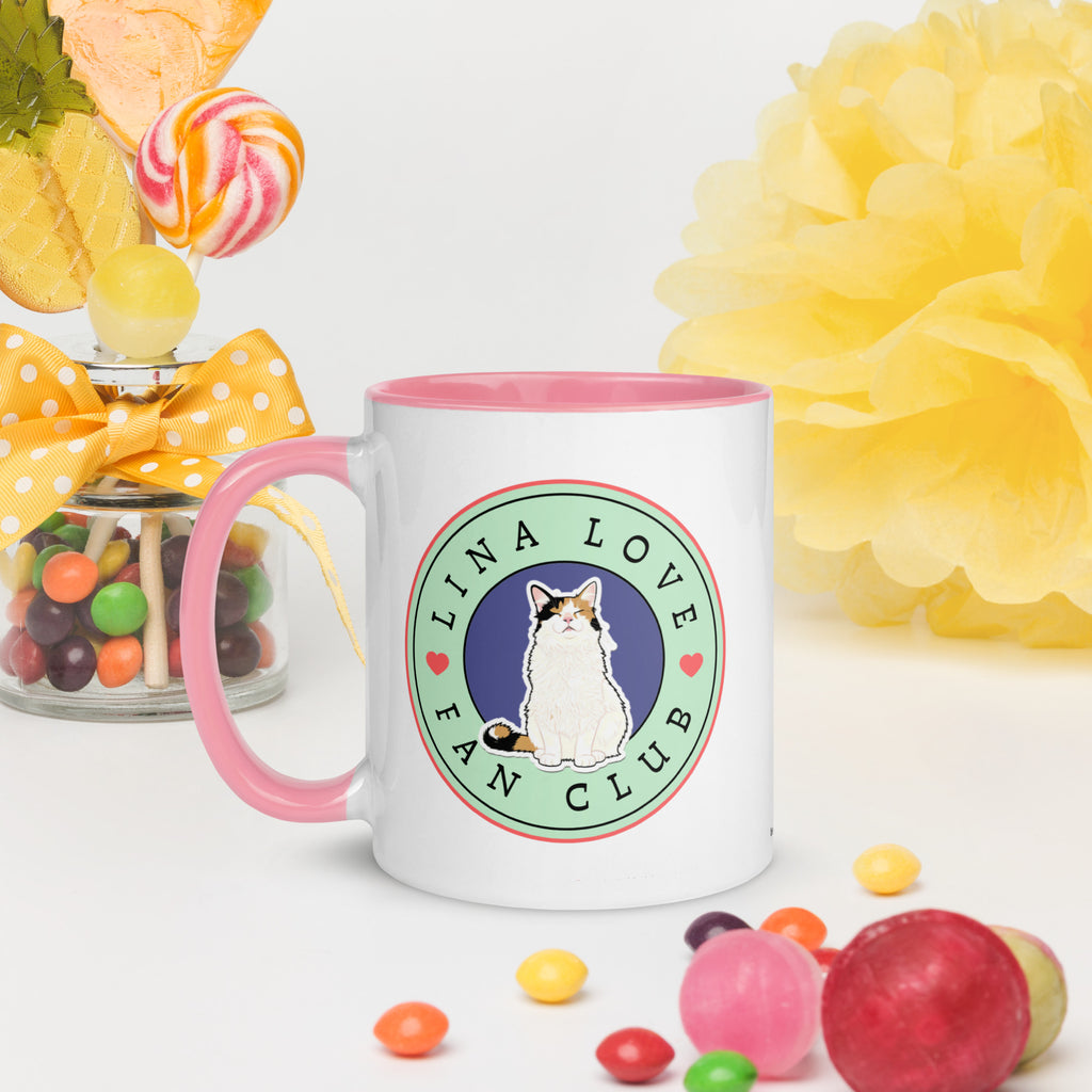 White ceramic mug with pink rim and handle featuring circular Lina Love Fan Club logo with calico cat illustration and heart accents.