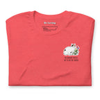 Folded heather red unisex t-shirt with Be Loving neck label and small Lina Love cat illustration with flowers and the text “The horrors persist, but so do the snacks” printed on the chest.