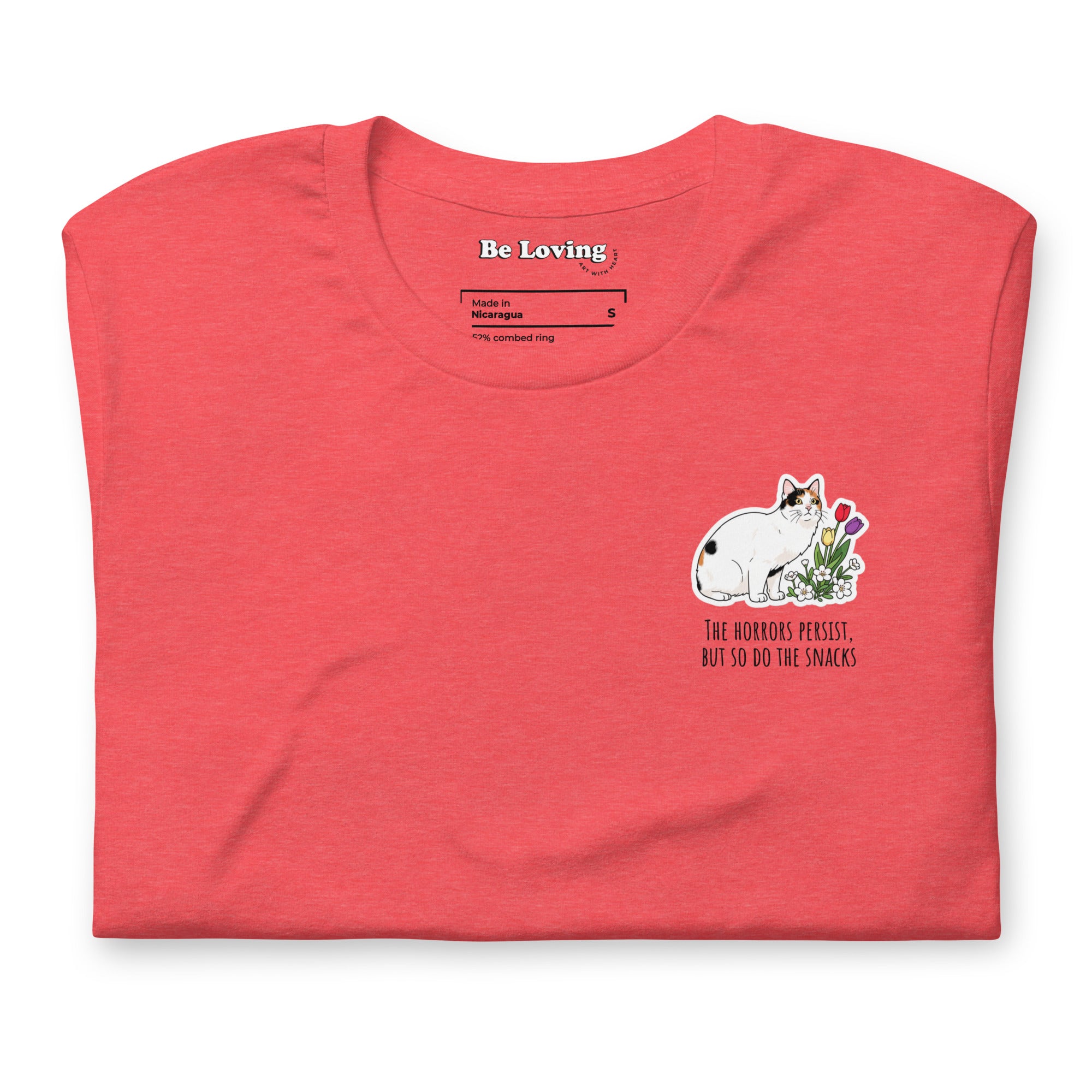 Folded heather red unisex t-shirt with Be Loving neck label and small Lina Love cat illustration with flowers and the text “The horrors persist, but so do the snacks” printed on the chest.