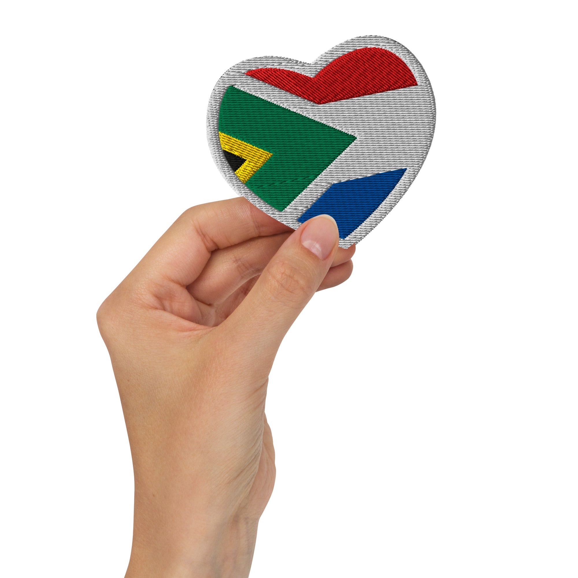 Hand holding a heart-shaped embroidered patch combining South African and Dutch flag colours, Two Homes One Heart South African Roots accessory.